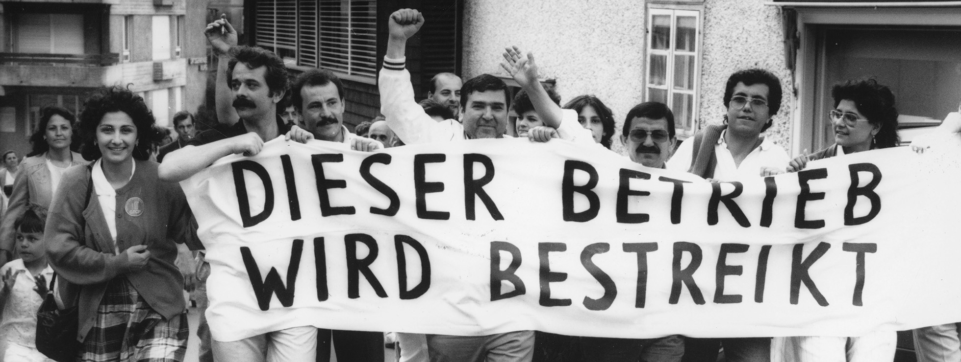 Arbeiter:innen demonstrieren. Vor sich tragen sie ein Transparent mit dem Text Dieser Betrieb wird bestreikt. © Schweizerisches Sozialarchiv F_5031-Fb-0197