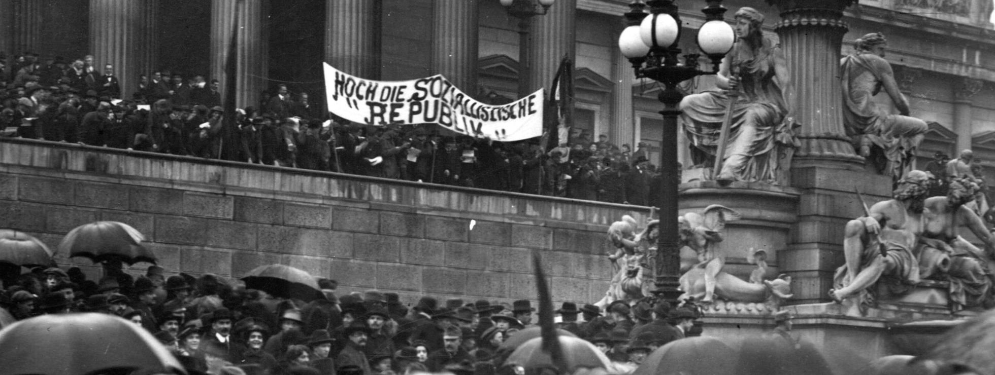 Bild von einer Demonstration vor dem Wiener Parlament, mittig ein Banner auf dem steht: "Hoch die Sozialistische Republik" © Wikimedia, gemeinfrei. Aufnahme von Richard Hauffe
