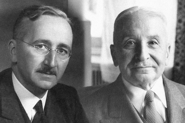 Beide tragen Anzüge, weiße Hemden und Krawatten. Sie haben Schnurbärte und ihr Haar nach hinten gekämmt.  Hayek trägt eine randlose Brille. © wikipedia