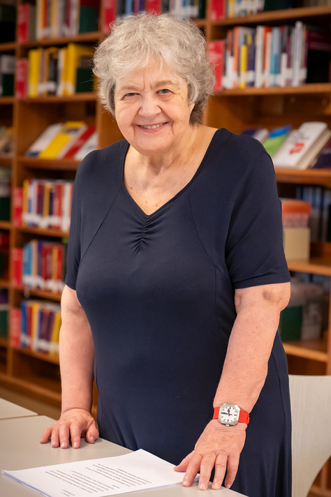 Brigitte Pellar tr&auml;gt kurze graue Haare und ein dunkel blaues Kleid. Sie steht in der AK Bibliothek und l&auml;chelt in die Kamera. &copy; &Ouml;GB / Roland de Roo