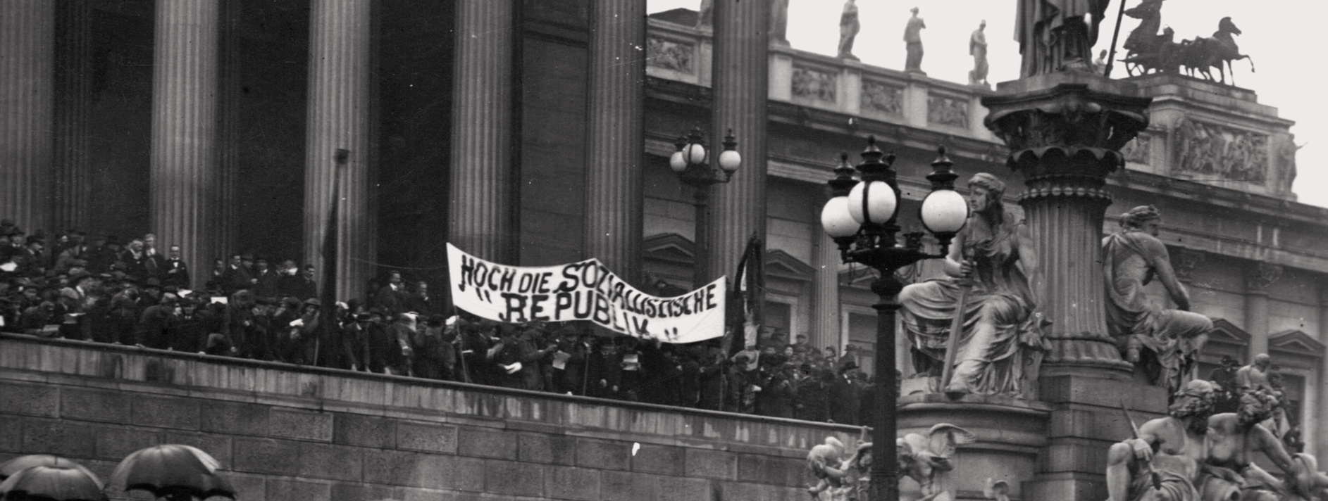 Bild von einer Demonstration vor dem Wiener Parlament, mittig ein Banner auf dem steht: "Hoch die Sozialistische Republik" © Wikimedia, gemeinfrei. Aufnahme von Richard Hauffe