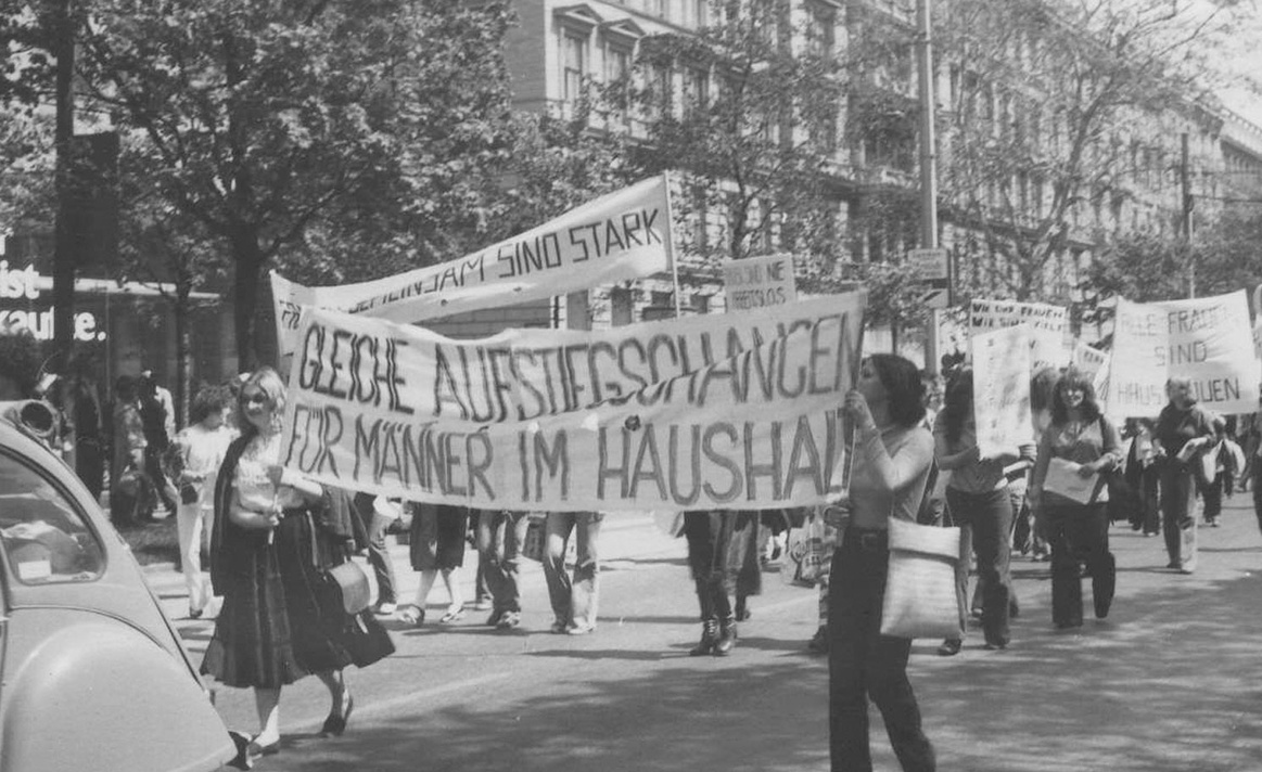 Ein Demonstrationszug, Frauen tragen Banner, auf dem vorne steht "Gleiche Aufstiegschancen f&uuml;r M&auml;nner im Haushalt", weiter hinten "Alle Frauen sind Hausfrauen". &copy; Burgi Hirsch, Kreisky-Archiv